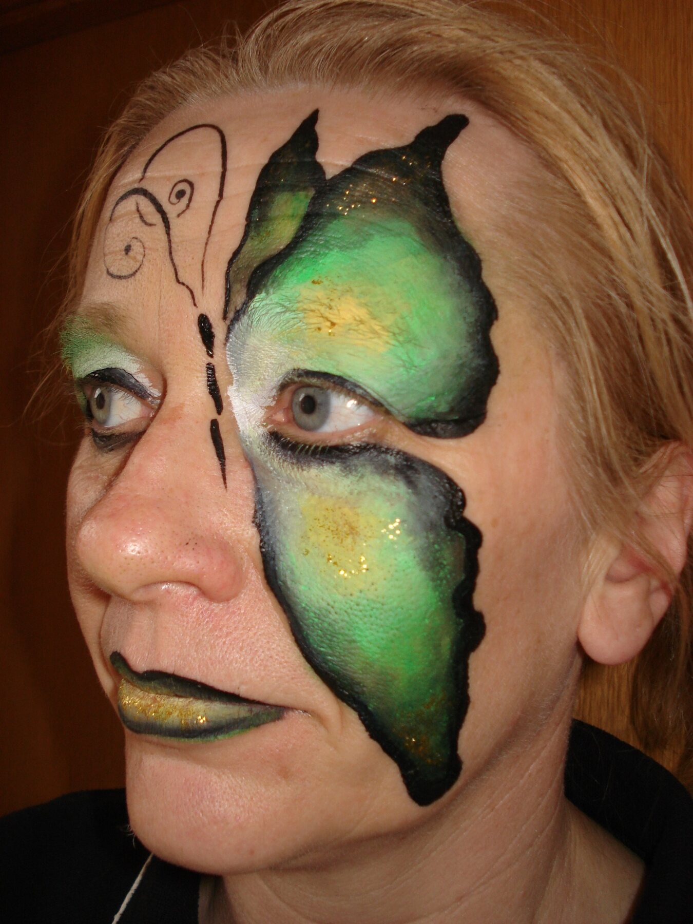 Green fantasy adult face-painting design by Hazel Wood