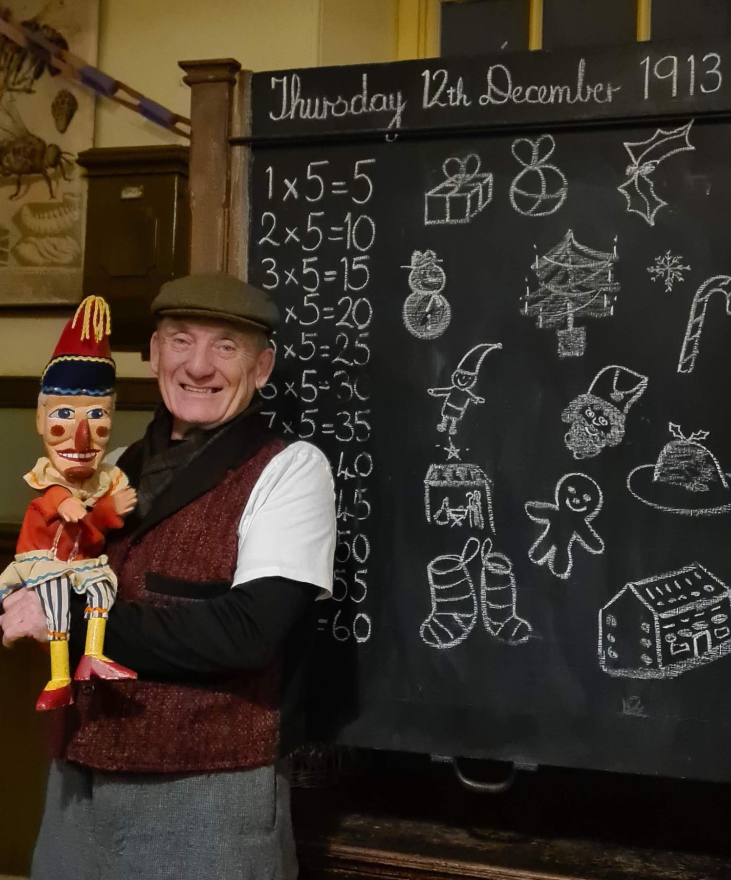 Professor Ron with Mr Punch beside a period classroom blackboard at Beamish
